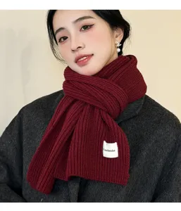 Close-up detail of the dark red ribbed knit winter scarf, soft texture and cozy warmth.