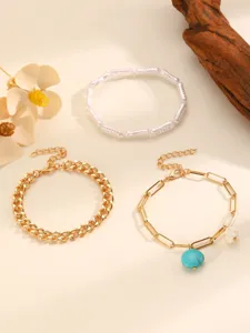 Detailed shot of a trendy multi-piece bracelet set featuring chains, beads and turquoise.