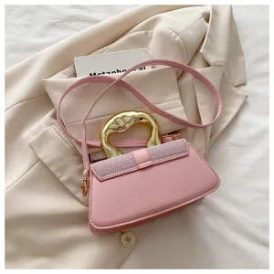 Stylish pink shoulder crossbody bag with unique gold sculptural handle and glitter flap detail.