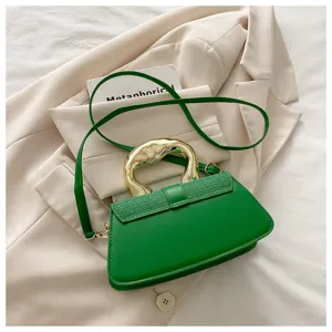 Green shoulder crossbody bag with unique metallic handle and belt detail, elegant design.