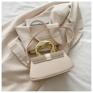 Chic beige shoulder crossbody bag with unique gold metal handle and sparkly rhinestone flap trim.