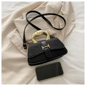 Detailed view of black women's shoulder crossbody bag with gold handle and metal clasp.