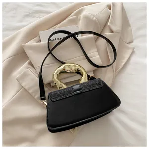 Close-up detail of the black crossbody bag with unique gold metallic handle and glitter flap.