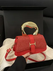 Chic red shoulder bag with gold handle and belt decor. Elegant crossbody style for women.