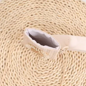 Vue detaillee du petit sac telefone tisse montrant la texture de paille et la doublure.