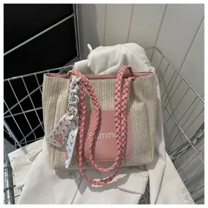 Detailed view of fashionable straw tote bag with braided pink straps and chic printed scarf.