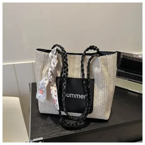 Large capacity woven straw tote bag with black handles and stylish front pocket detail.
