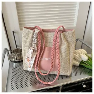 Straw tote bag detail showing pink braided handles and front pocket with summer print.