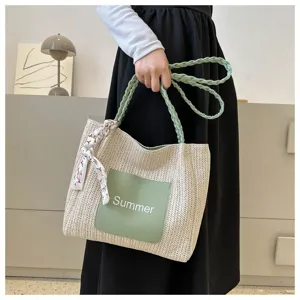Detailed view of a trendy straw woven shoulder tote bag with green pocket and decorative scarf.