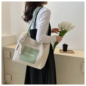 Detailed view of the stylish woven straw tote bag with green pocket and floral accessory.