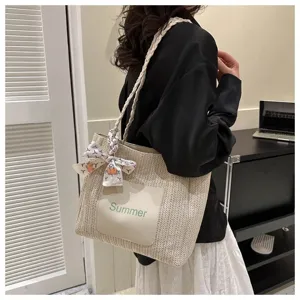 Detailed view of women's woven straw tote bag with braided strap and Summer letter patch.