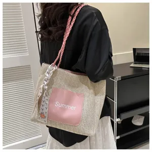 Detail view of woven straw tote bag with pink front pocket and ribbon decoration, ideal for summer.