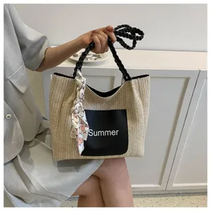 Detailed view of the straw tote bag with black braided handles and Summer pocket.
