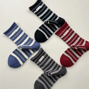 Detailed view of women retro striped mid-tube socks with cute fabric label and rolled cuffs.