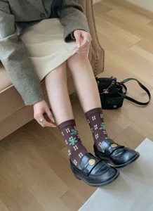 Detailed close-up of brown floral plaid mid-calf cotton socks worn with black shoes.