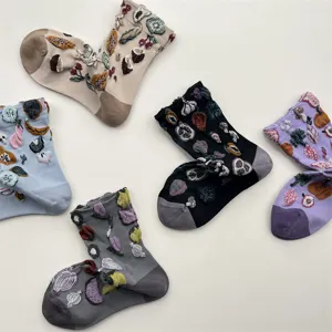 Close-up detail of cozy cotton crew socks featuring cute 3D embroidered fruit and vegetable patterns.