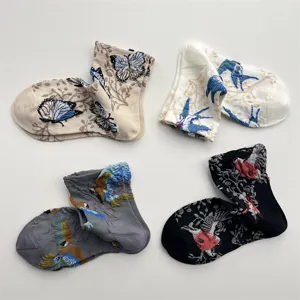 Detailed view of embroidered cotton mid-calf socks featuring retro butterfly and bird patterns.
