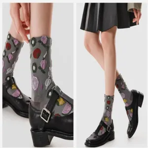 Close-up detail of grey novelty socks with cute fruit and vegetable embroidery pattern.