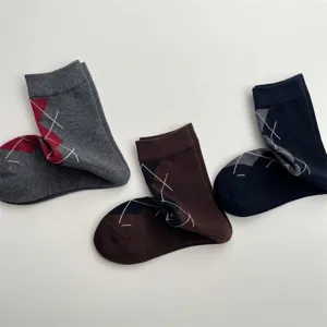 Primo piano dettaglio di calzini a metà gamba fantasia argyle con ricamo a croce.