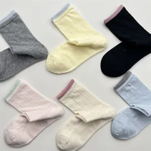 Detail shot of hollow mesh vine knit texture and contrast color cuffs on cotton socks.