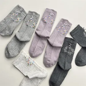 Close-up detail of cute floral wreath embroidered mid-tube cotton socks with bows.