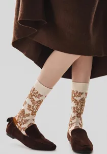 Close-up detail shot of retro floral embossed cotton mid-tube socks paired with brown loafers.