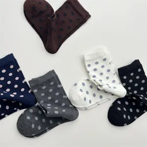 Gros plan d'un assortiment de chaussettes mi-mollet en coton à pois colorés style doux.