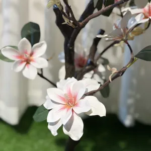 Detailopname van kunstmatige witte en roze magnoliabloemen met takken voor interieurdecoratie.