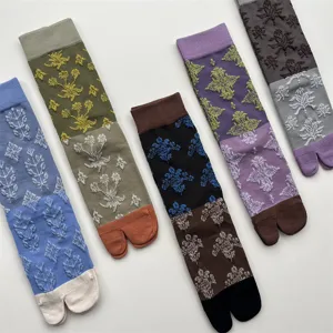 Gros plan de chaussettes tabi rétro avec motifs floraux en relief et design color-block.