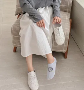 Close-up detail of breathable mesh boat socks worn with casual white sneakers in lifestyle scene.