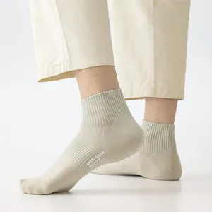 Gros plan détaillé de chaussettes de cheville unies respirantes pour hommes en kaki clair.
