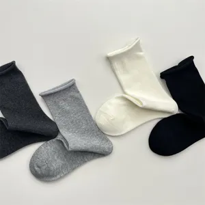 Dettaglio di calzini tinta unita con risvolto arrotolato, cotone morbido e traspirante.