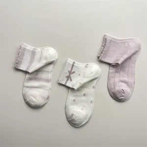 Nahaufnahme von niedlichen Frühlings-Baumwollsocken mit Streifen, Schleifen und Rüschen.