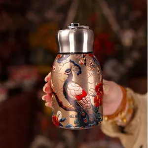 Close-up of portable mini thermos cup featuring traditional Chinese peacock and floral pattern.