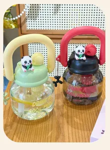 Vue détaillée de la jolie bouteille d'eau transparente avec charmante petite poupée panda.