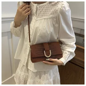 Dettaglio borsa a tracolla marrone con stampa coccodrillo, elegante chiusura in metallo a U.