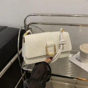 Primo piano dettagliato della borsa a tracolla bianca coccodrillo con chiusura dorata a U.