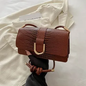 Dettaglio borsa a tracolla marrone coccodrillo, ecopelle texturizada con chiusura in metallo.