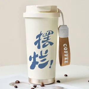Stainless steel coffee cup detail view, portable insulated mug with cute text and handy strap.