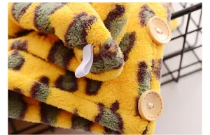 Close-up of soft coral fleece hair drying cap texture, showing wooden button and elastic loop.
