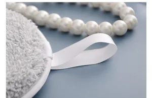 Primer plano detallado de la almohadilla facial de felpa gris con lazo de saten blanco.