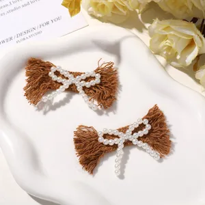Detailed shot of brown fabric faux pearl bow hair clip, elegant handmade DIY accessory.