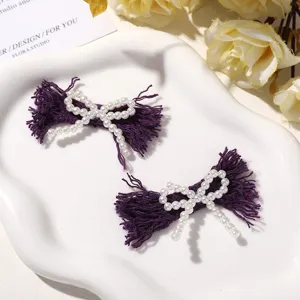 Detailed shot of purple fringed fabric bow adorned with pearls, handmade DIY accessory.