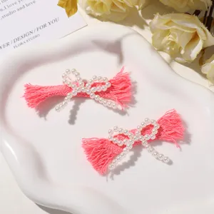 Close-up detail of handmade pink fabric bow hair clips embellished with elegant faux pearls.