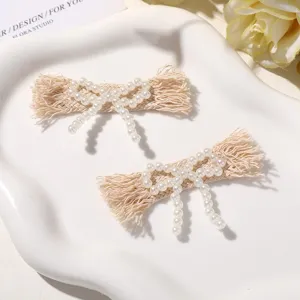 Close-up detail of lovely beige fabric hair clips decorated with faux pearls in bow design.