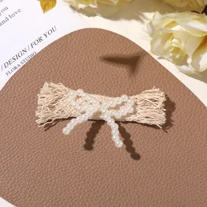 Detailed close-up of faux pearl fabric bow hair accessory, craft DIY clothing shoe decoration.