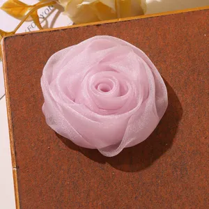 Vue de détail rapprochée d'un accessoire DIY fleur de rose en organza rose, texture douce.