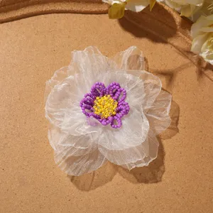 Close-up detail of white organza beaded flower applique with purple and yellow center for DIY craft.