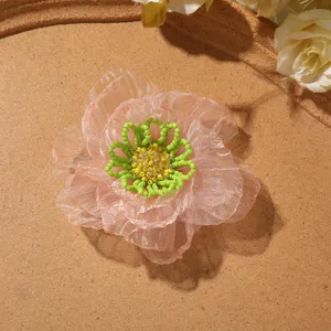 Close-up detail of pink organza burnt edge flower with green beaded stamen for DIY craft.