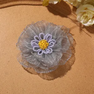 Close-up of grey organza flower brooch with beaded petals and yellow bead center detail.